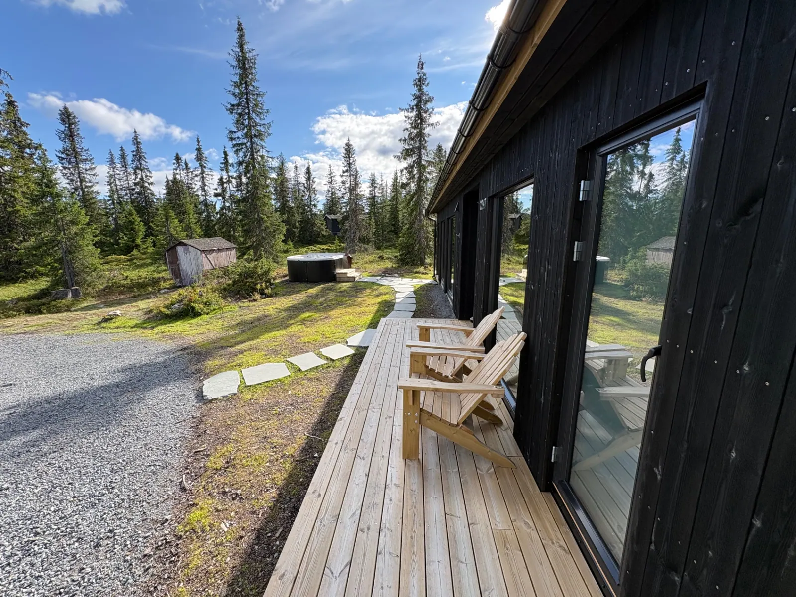 Utsikt fra terrassen mot boblebad og granskog
